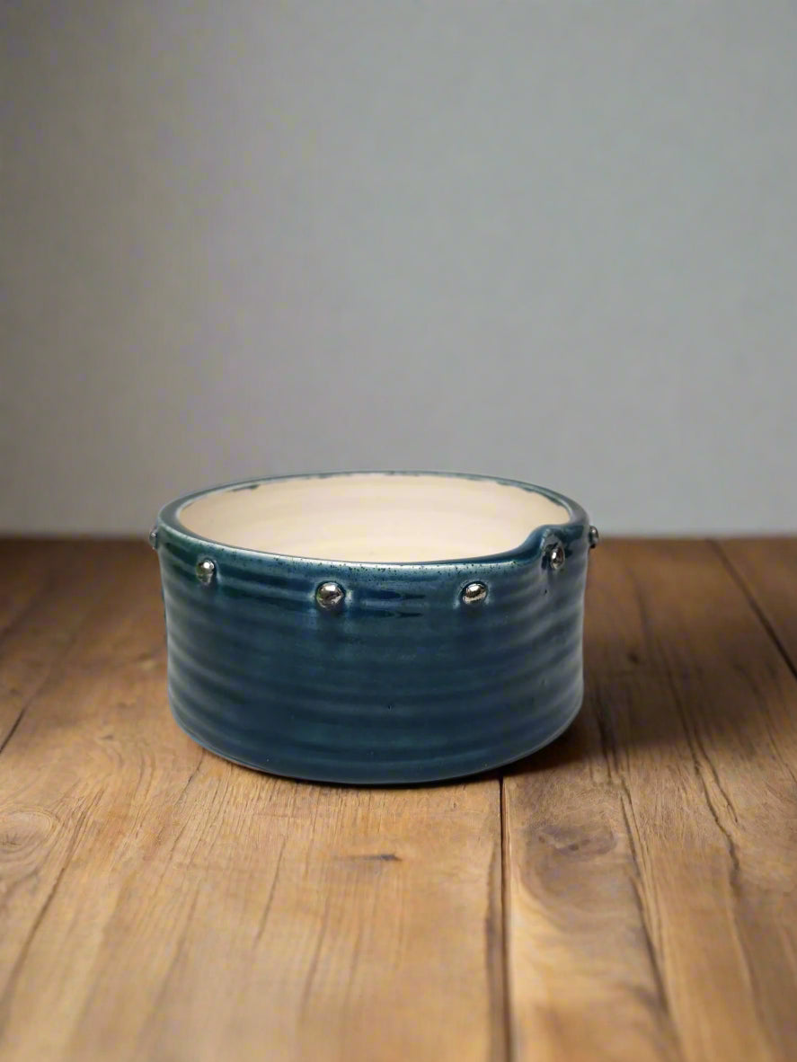 Handcrafted medium-sized ceramic dog bowl with an asymmetrical rim and platinum lustre rivet details. Organic shape inspired by ocean waves.